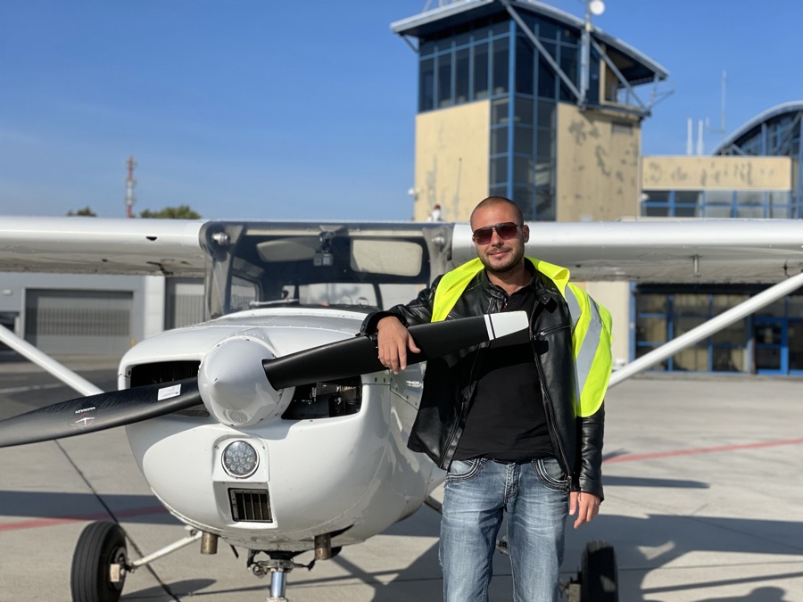 Mykyta Karpyshyn standing in front of a light aircraft at an airfield